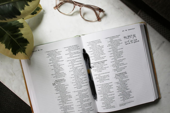 Open Bible with pen and glasses on a marble surface
