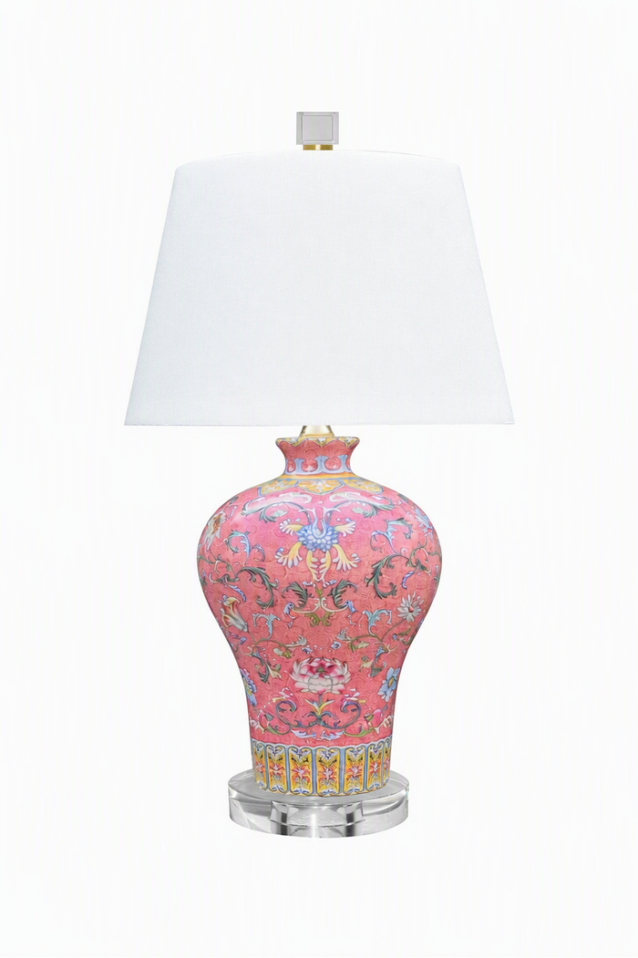 A table lamp with a pink porcelain-style vase base decorated with multicolored floral and scroll patterns, a white tapered lampshade, and a clear acrylic round base, shown on a white background.
