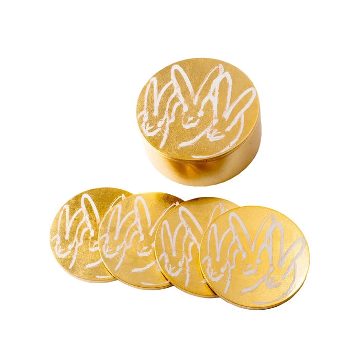 Set of gold coasters with white rabbit design on a white background