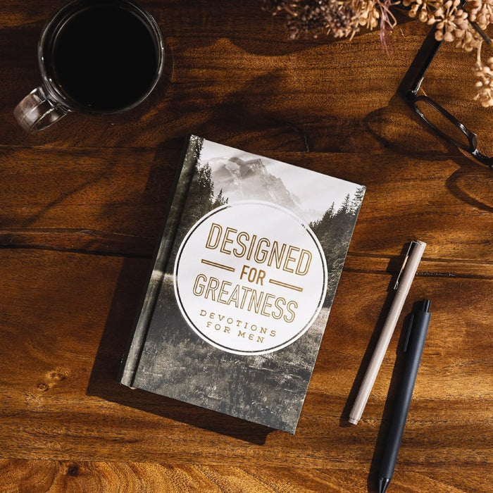 Devotional titled 'Designed for Greatness' on a wooden surface with a mug and pen.