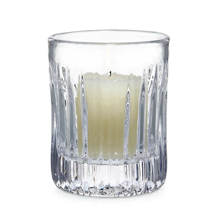 Clear glass candle holder with a white candle on a white background
