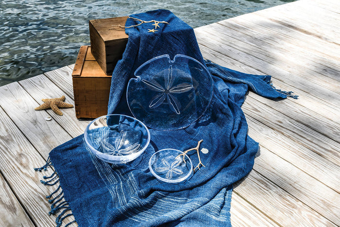 Blue towel with sand dollar designs on a wooden dock by water