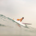 A woman in a white and golden yellow swimsuit paddling into a cresting wave on a longboard, shot from water level in foggy light in the fine art photograph SOFT LAUNCH by Craig Hubbard.