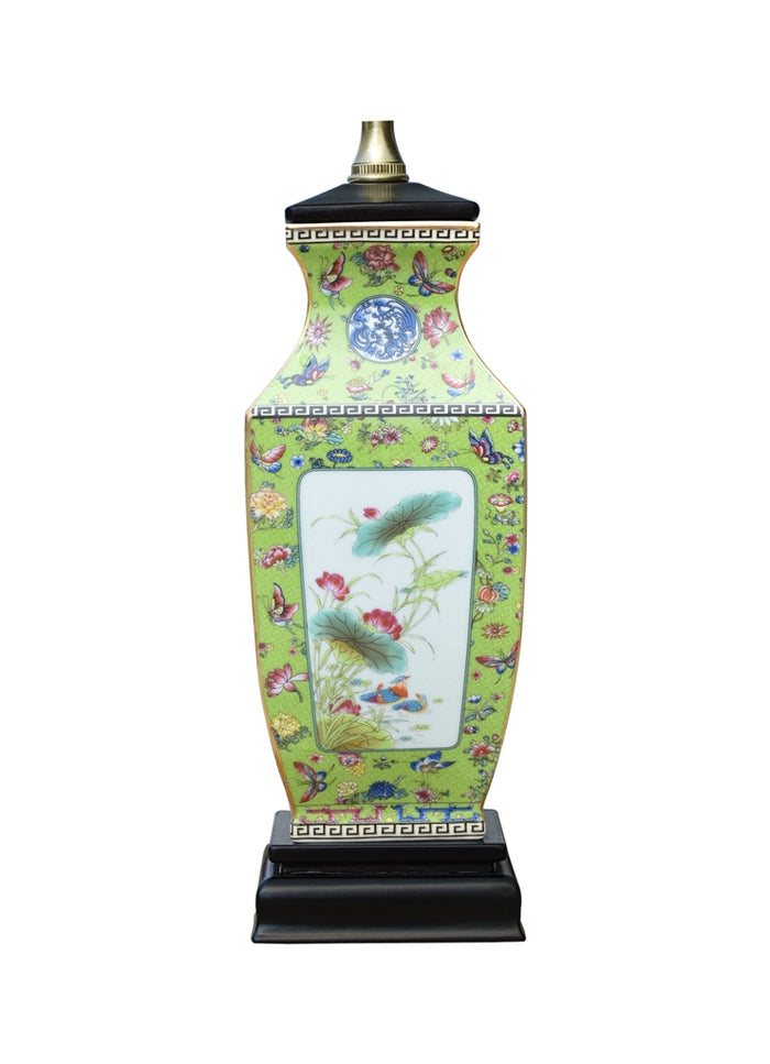 A tall decorative table lamp shaped like a porcelain vase, featuring a light green body with a colorful floral and butterfly pattern, a central white panel depicting lotus flowers, and a black base with a gold finial.
