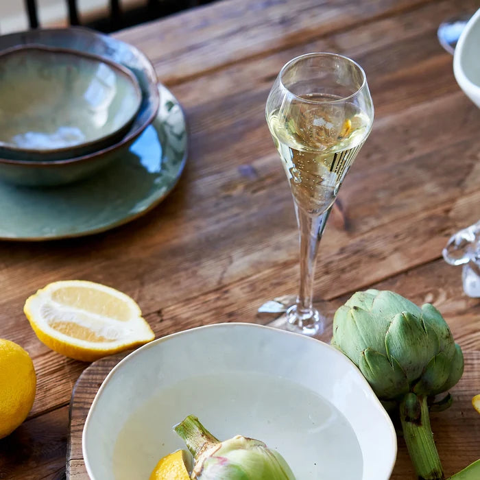 Glass of champagne on a wooden table with lemons and artichokes.